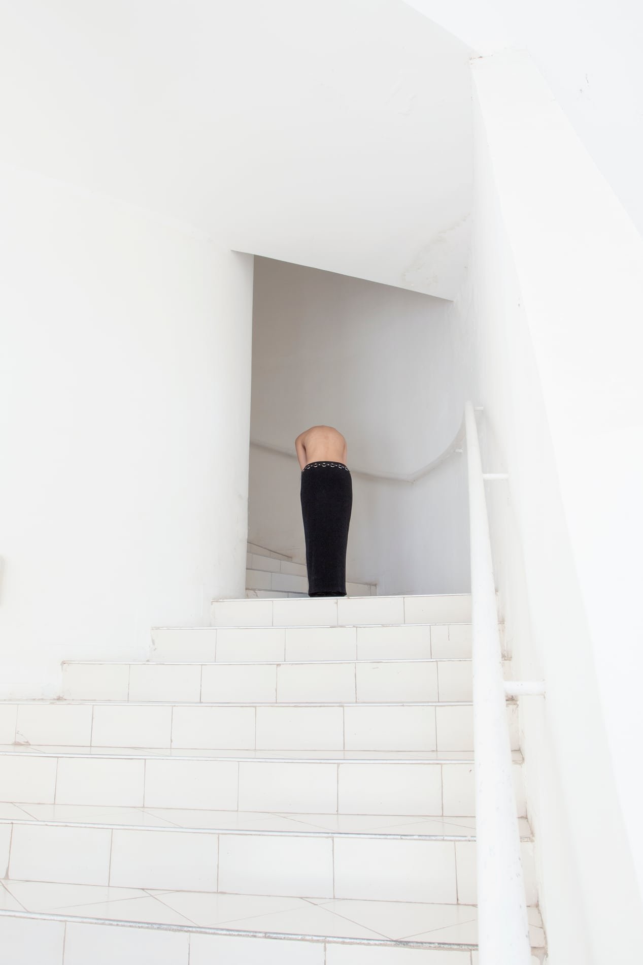 Figure descending a white stairwell