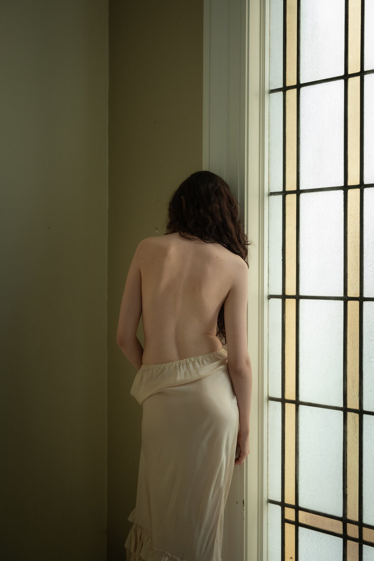 Bare back portrait by a leaded window